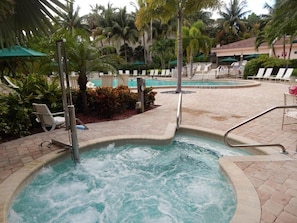 Un jacuzzi rodeado de sillas de descanso y palmeras.