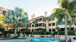 Un hotel con piscina rodeada de palmeras y sillas de descanso.