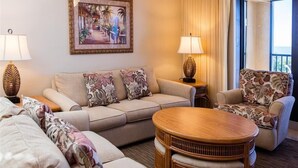 Une chambre d’hôtel avec un canapé, une table basse ronde et deux lampes.