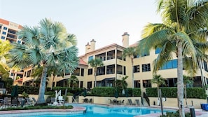 Un hôtel doté d’une piscine entourée de palmiers et de chaises longues.