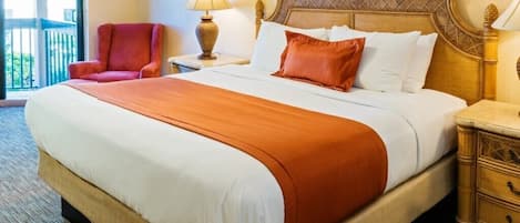 A hotel room with a large bed, a nightstand, a lamp, a chair, and a view of the outdoors.