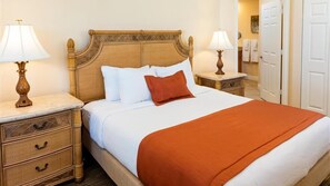 A neatly made bed with a wooden headboard, two bedside tables with lamps, and a red throw blanket.