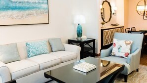 A living room with a sofa, armchair, coffee table, and a lamp.