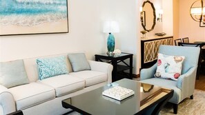 A living room with a sofa, armchair, coffee table, and a lamp.