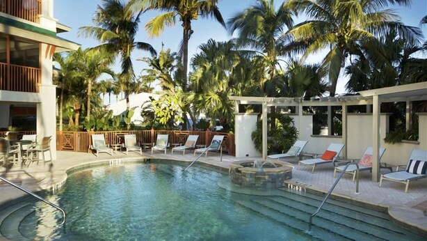 A pool area with lounge chairs and palm trees.