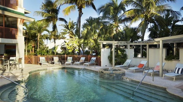 A pool area with lounge chairs and palm trees.