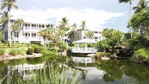 Ein Resort mit einem Wasserspiel, einschließlich eines Gazebos, Palmen und einem großen Gebäude mit mehreren Balkonen.