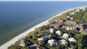Eine Luftaufnahme eines Küstenresorts mit Strandimmobilien, einem großen Gebäudekomplex und freiem Blick auf den Ozean.