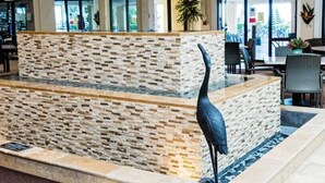 Eine Lobby mit einer Steinwand, einer Skulptur eines schwarzen Vogels und Sitzmöglichkeiten.