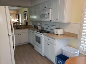 Cocina compacta con gabinetes blancos, microondas, tostadora y lavamanos.