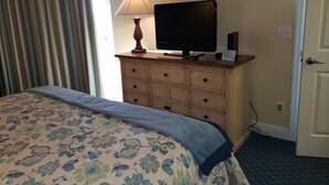 Une chambre d’hôtel avec un lit, un téléviseur posé sur une commode et une porte.