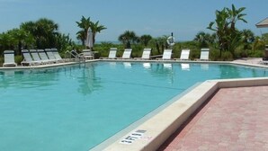 Ein Schwimmbecken mit Liegestühlen und Palmen.