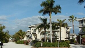 Un quartier résidentiel avec des immeubles à plusieurs étages, des palmiers et une allée gravillonnée.