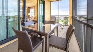 A balcony with wicker furniture, a glass table, and a view of the interior. - Marco Island | Family Waterfront Stay | Pool + Marina | 3BR Sleeps 8 (Marco Island)