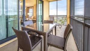 Un balcón con mobiliario de mimbre, una mesa de vidrio y vistas a la ciudad.