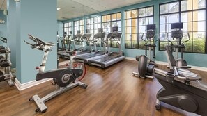 Un gimnasio con cintas de correr, elípticas y equipo de pesas.