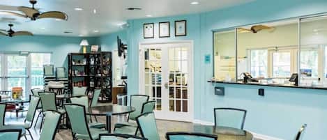 A room with teal walls, a large window, a reception desk, and a bookshelf.