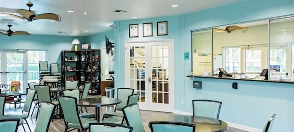 A room with teal walls, a large window, a reception desk, and a bookshelf.