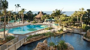 A resort pool area with multiple pools, lounge chairs, and palm trees.