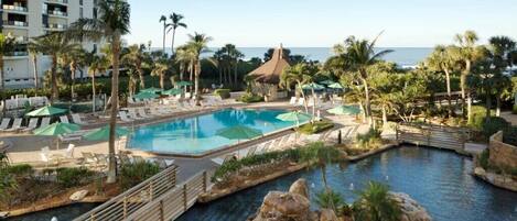 A resort pool area with multiple pools, lounge chairs, and palm trees.
