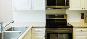 Una cocina con un lavamanos de acero inoxidable, un microondas, un horno y un tostador.