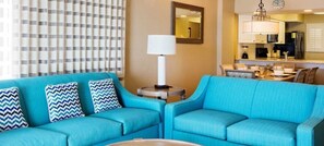 Una sala de estar con un sofá azul, una mesita redonda y una lámpara.