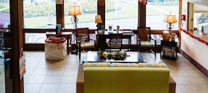 Un hall de hotel con zona de estar, mostrador de recepción y vistas al exterior.
