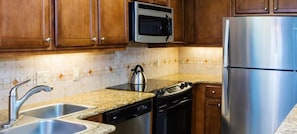 Una cocina con electrodomésticos de acero inoxidable, lavavajillas y microondas.