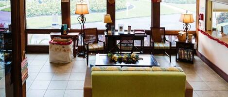 A hotel lobby with a seating area, a reception desk, and a view of the outdoors.