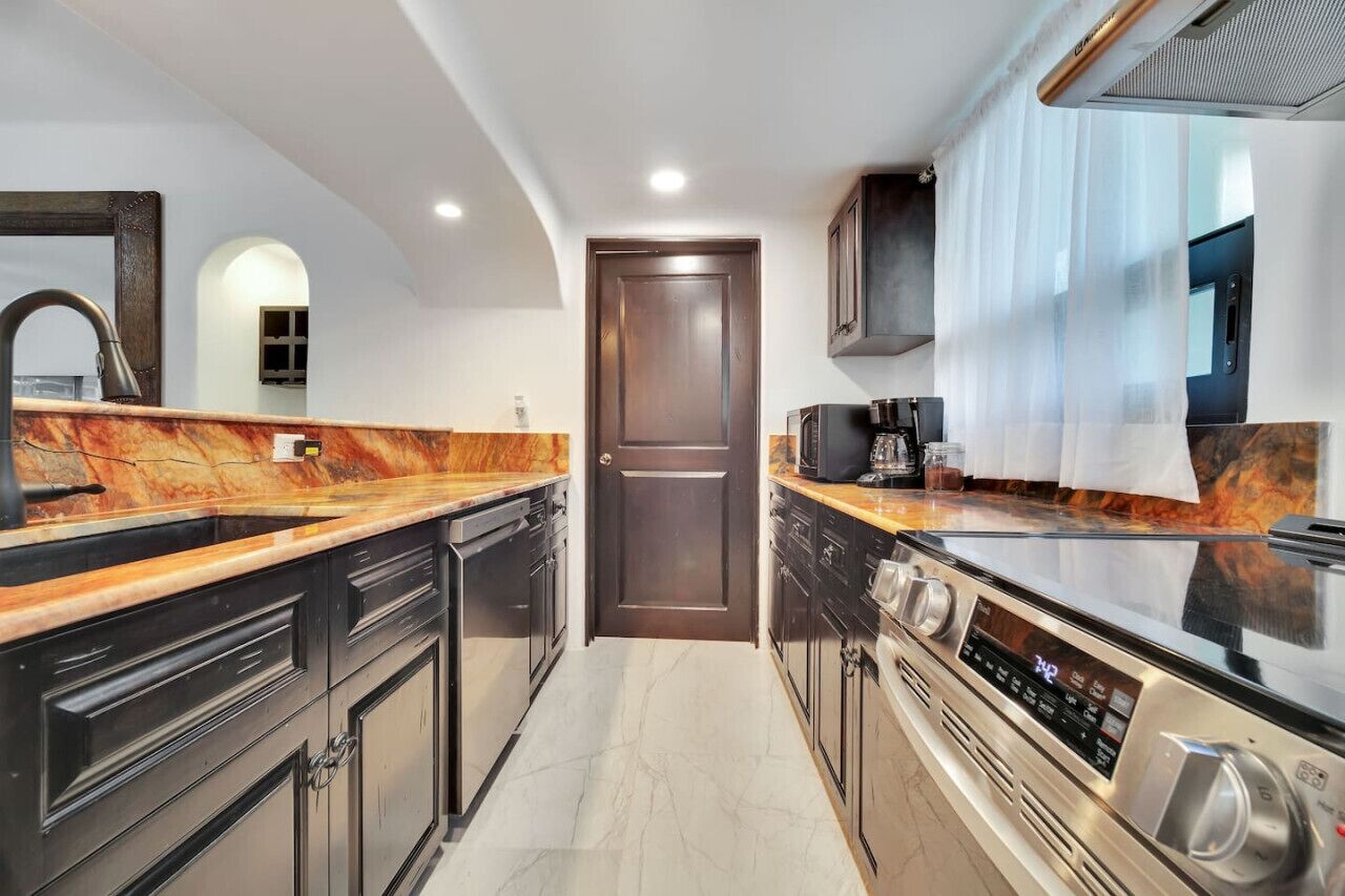 Una cocina moderna con armarios oscuros, encimera de mármol y horno empotrado.