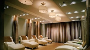 Un cuarto de spa con varias zonas de estar, un ventanal con cortinas e iluminación en el techo.