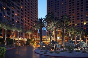 A hotel with multiple high-rise buildings, palm trees, and a well-lit entrance area. - Las Vegas | Pool & Strip Access | 2BR Plus (Las Vegas)