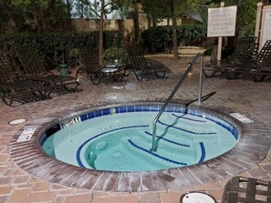 A hot tub with a tiled edge, surrounded by lounge chairs and a brick patio. - Las Vegas | Pool & Strip Access | 2BR Plus (Las Vegas)