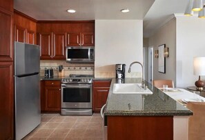 A modern kitchen with wooden cabinets, stainless steel appliances, and a granite countertop. - Las Vegas | Pool & Strip Access | 2BR Plus (Las Vegas)