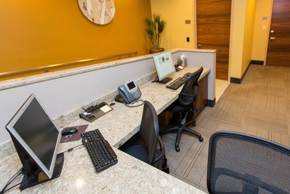A hotel reception desk with a computer, phone, and keyboard.