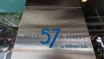 A metallic sign with 'WEST 57th STREET by Hilton Club' written on it.
