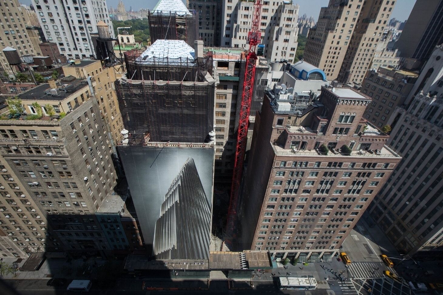 A high-rise building with a distinctive spire, surrounded by other tall buildings and construction cranes.