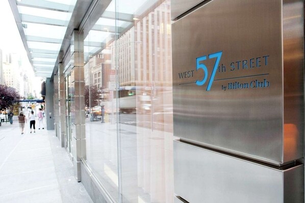 A modern building with a glass facade and a sign indicating '57th Street by Hilton Club.'