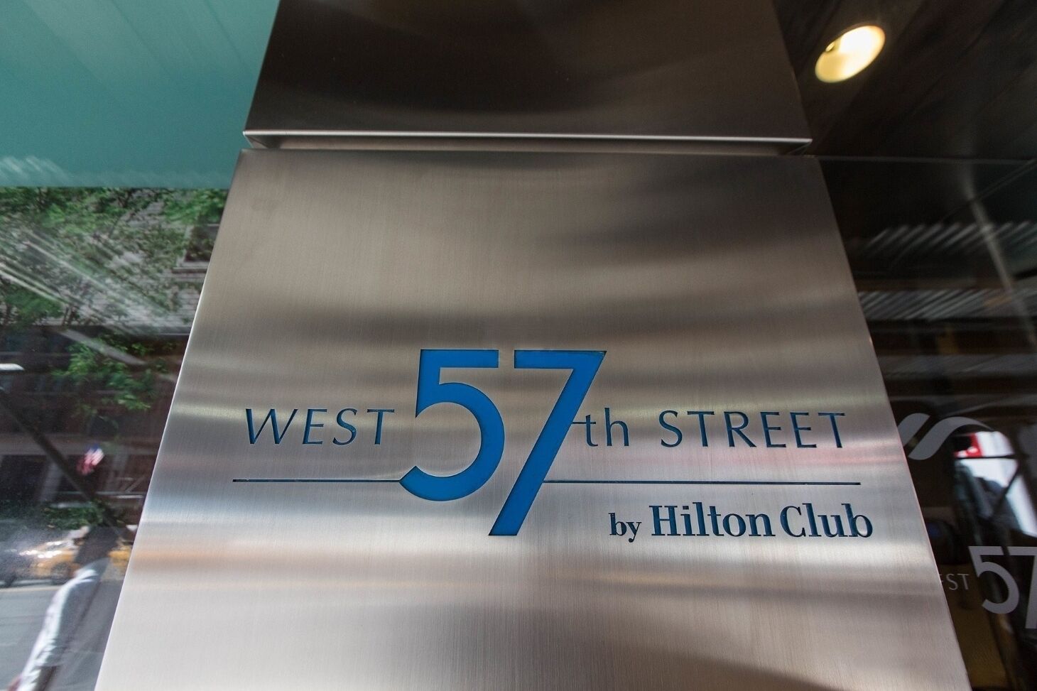 A metallic sign with 'WEST 57th STREET by Hilton Club' written on it.