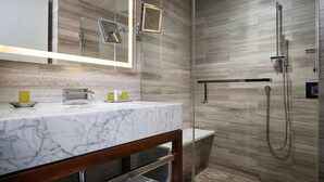 A modern bathroom with a marble vanity, a glass shower enclosure, and wooden paneling on the walls. - NYC | Midtown Location | Central Park | Studio (New York)