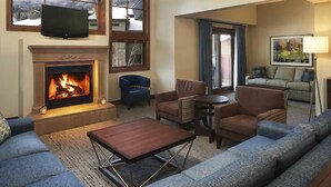A living room with a fireplace, sofas, a television, and a view of the outside. - Park City | Group Powder Base | Pool + Hot Tub | 4BR | Sleeps 10 (Park City)