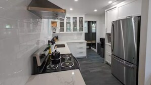 A modern kitchen with white cabinets, a stainless steel refrigerator, and a black stove.