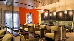 A hotel lobby with seating areas, a reception desk, and artwork on the walls. - Orlando | Upscale Disney Retreat | Pool + Parks (Orlando)