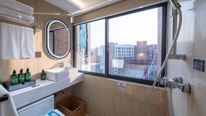 A modern bathroom with a large window, a sink, two mirrors, and a shower.