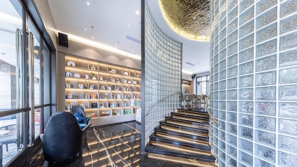 A modern interior with a staircase, a bookshelf, and a seating area.