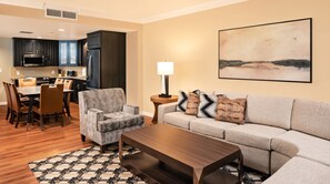 A modern living room with a sofa, armchair, coffee table, and dining area with chairs and a table. - Orlando | Upscale Disney Retreat | Pool + Parks | 2BR (Orlando)