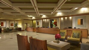 Een hotel lobby met een receptiebalie, een zithoek en kunstwerken aan de muren.