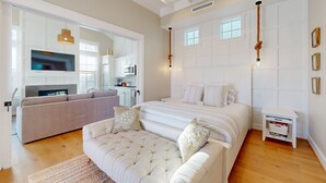 A spacious bedroom with a large bed, a sofa, and a TV in the adjacent living area. - Resort Pools, Golf Cart Boardwalk to Beach (Port Aransas)