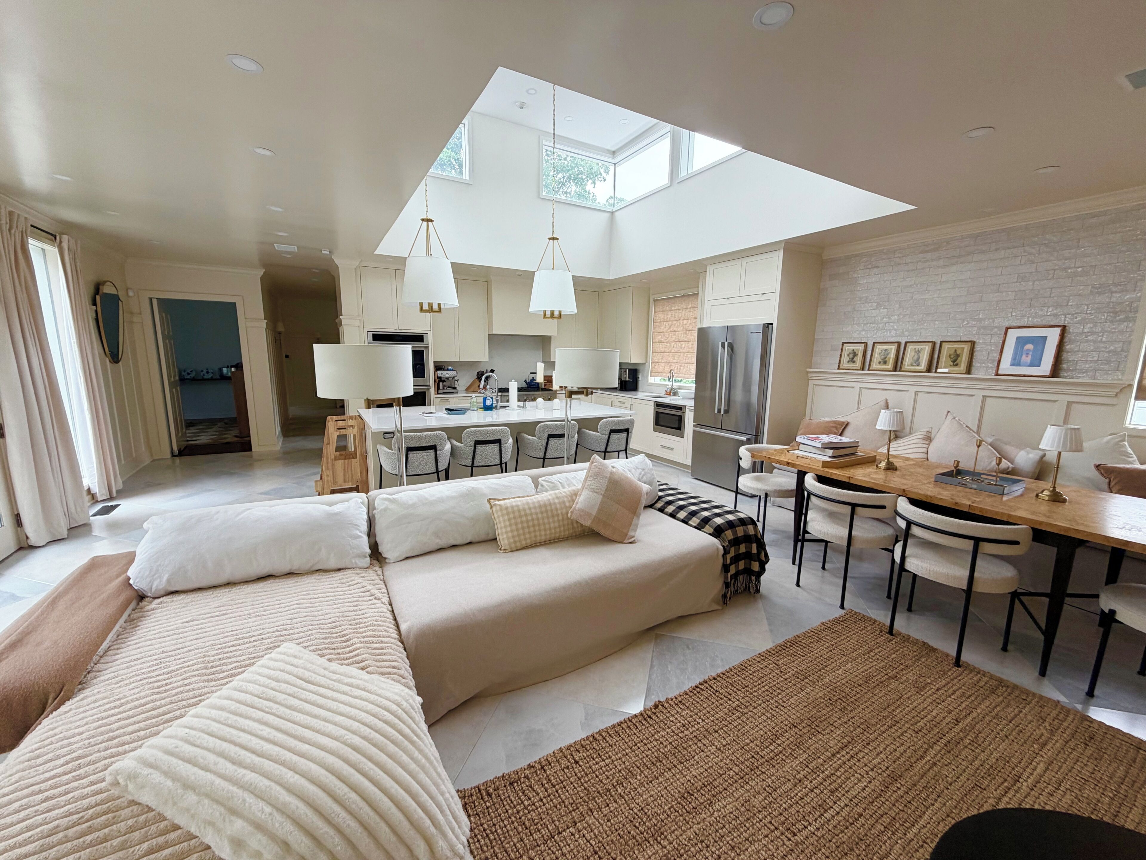 A modern living room with a sofa, a dining area, and a kitchen.