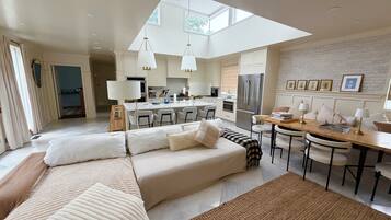 A modern living room with a sofa, a dining area, and a kitchen.